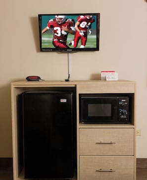 A kitchenette with a refrigerator, microwave, and a television mounted on the wall. - Red Roof Inn & Suites Pigeon Forge - Parkway (Pigeon Forge)