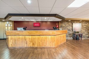 Un mostrador de recepción con un cartel que dice 'Wi-Fi gratis en todas las habitaciones', una pared de piedra y un cartel de 'Red Roof Inn'.