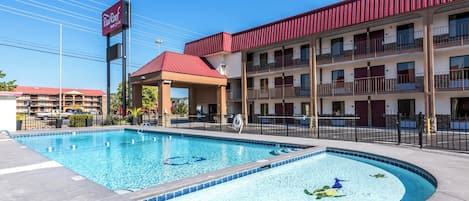 Un hôtel doté d’une piscine, d’un espace couvert et d’un bâtiment au toit rouge.