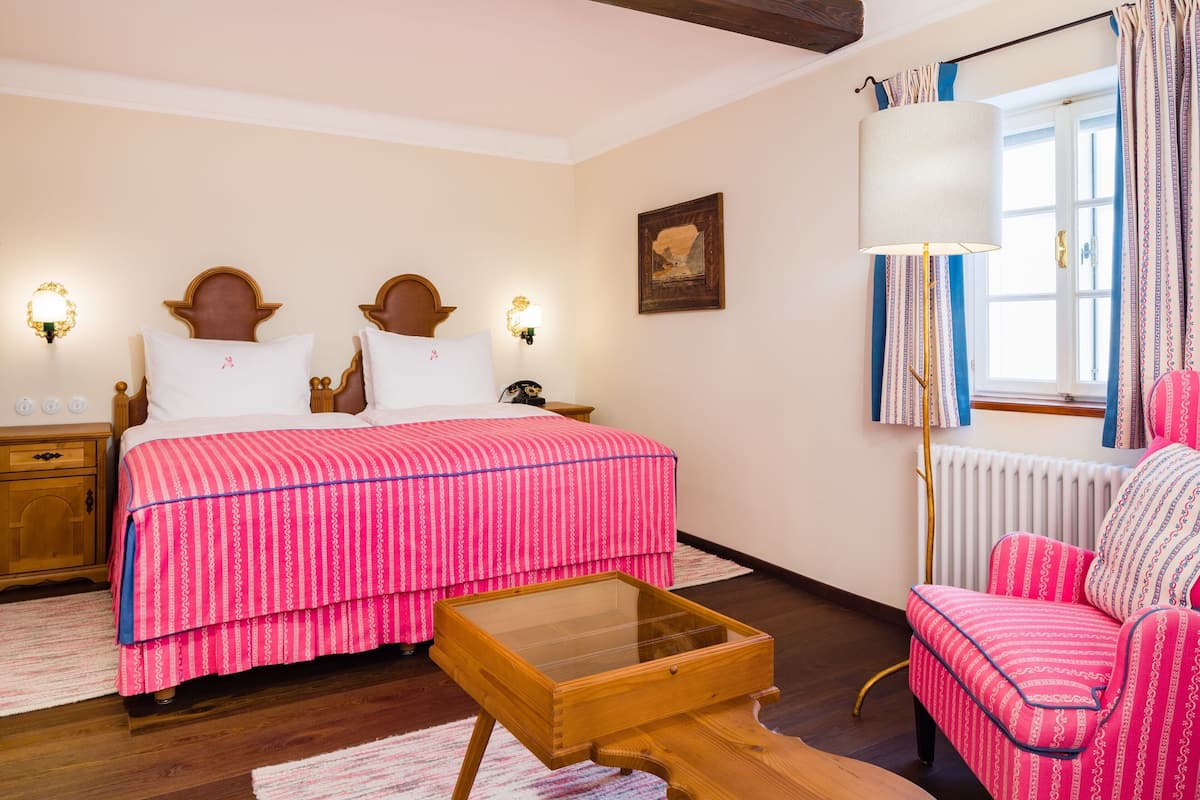 A bedroom with a bed, bedside tables, a lamp, a chair, and a window with curtains.