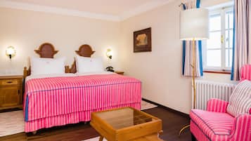 Une chambre à coucher avec un lit, des tables de chevet, une lampe, une chaise et une fenêtre avec des rideaux.