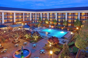 A hotel with a swimming pool, outdoor seating, and a courtyard.