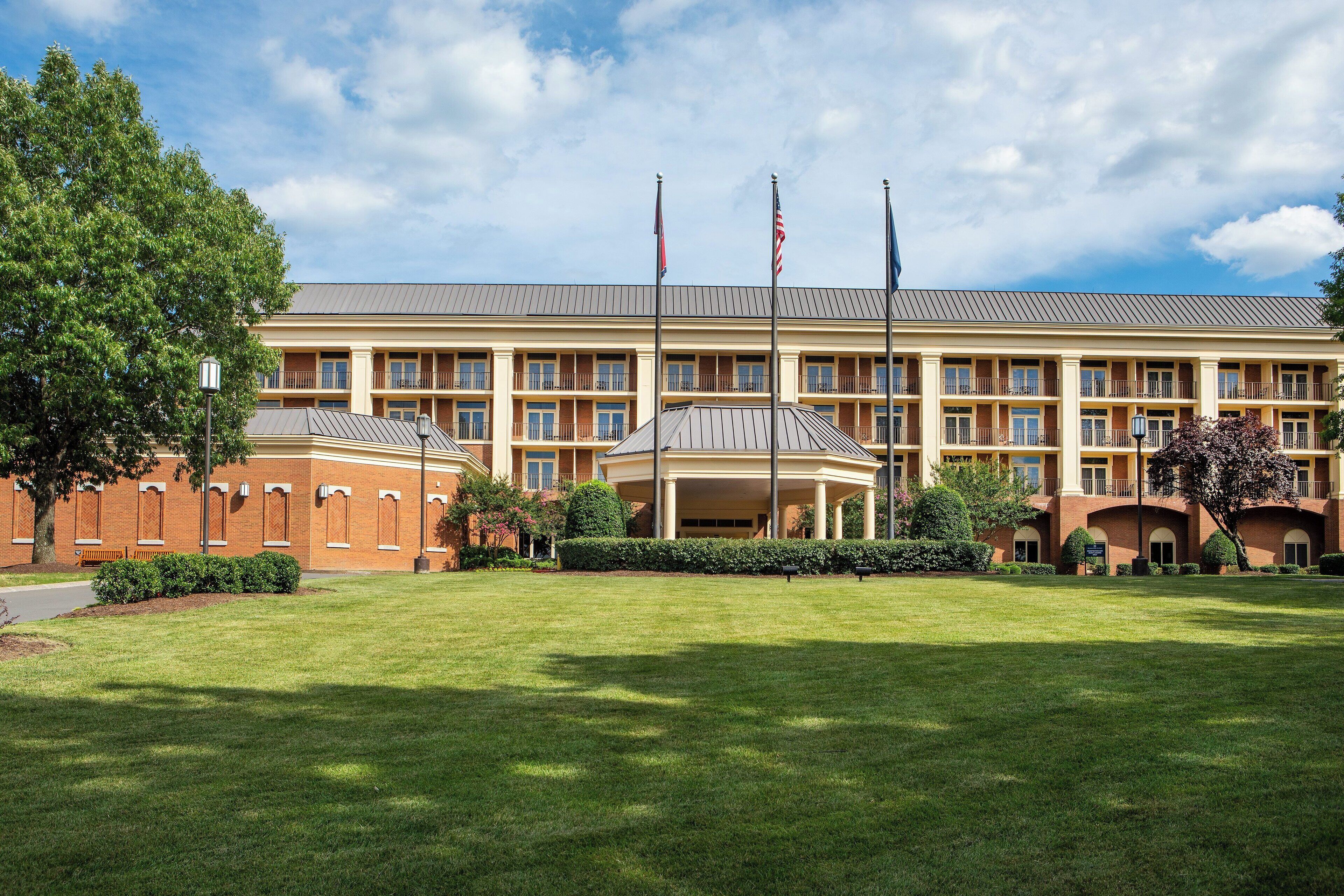 A large, multi-story building with a central courtyard, flagpoles, and a well-maintained lawn.
