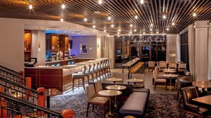 A modern hotel lobby with a bar, seating areas, and a staircase. - Sheraton Music City Nashville Airport (Nashville)
