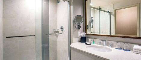 Un baño moderno con cabina de ducha de vidrio, lavabo con espejo y un perchero para toallas.