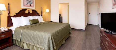 A hotel room with a bed, bedside lamps, a television, and a painting on the wall.
