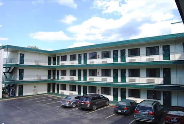 A motel with a two-story structure, multiple rooms, and a parking lot with several cars.