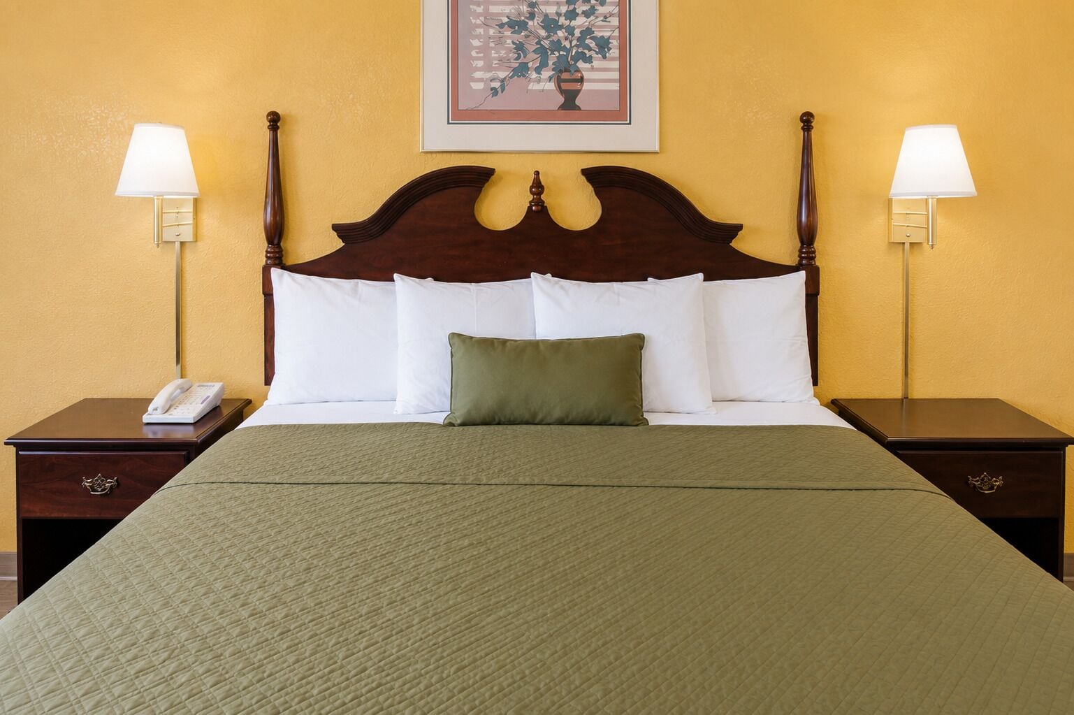 Habitación de hotel con una cama grande, dos mesitas de noche, un teléfono y dos lámparas de pared.