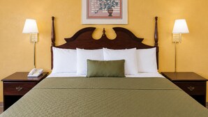 Habitación de hotel con una cama grande, dos mesitas de noche, un teléfono y dos lámparas de pared.