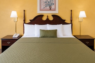 Habitación de hotel con una cama grande, dos mesitas de noche, un teléfono y dos lámparas de pared.