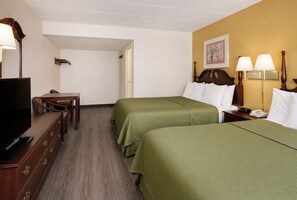 Habitación de hotel con dos camas, televisión, escritorio y una silla.