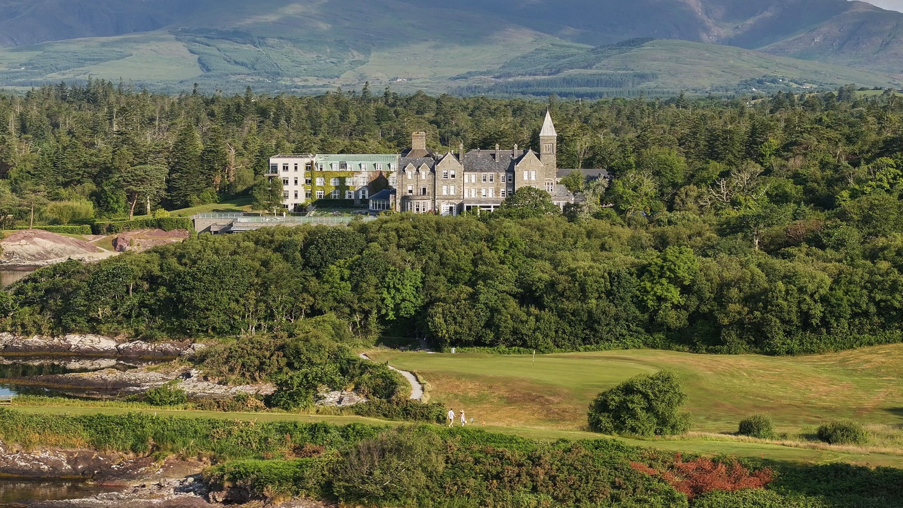 Un edificio grande e histórico con múltiples torres y un paisaje circundante bien cuidado.