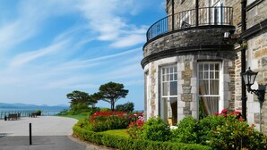 A corner building with stone walls, a balcony, and a view of the sea. - Parknasilla Resort and Spa (Sneem)