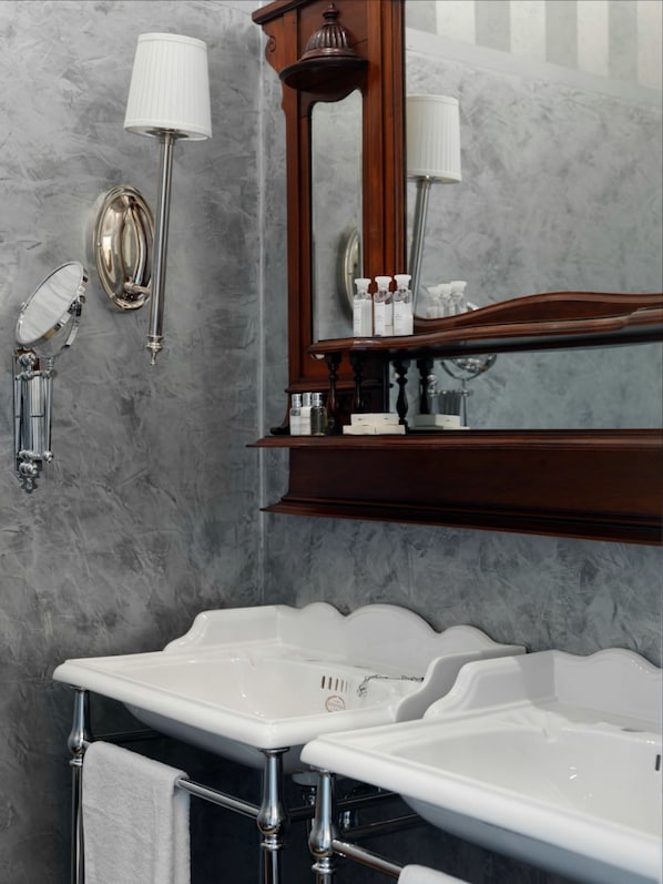 A bathroom with two white sinks, a large mirror, and wall-mounted lighting fixtures.