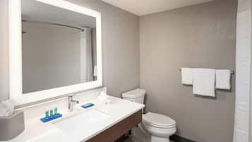 Un baño moderno con lavamanos, espejo y retrete blancos.
