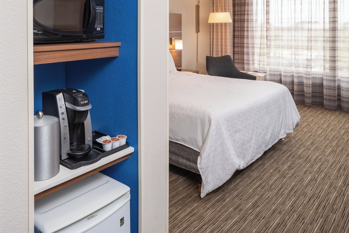 Een hotelkamer met een bed, een koffieapparaat, een magnetron en een nachtkastje.