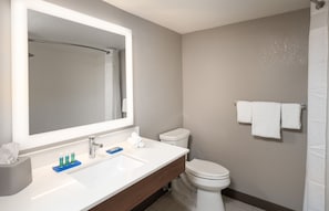 Een moderne badkamer met een grote spiegel, een wit wastafelmeubel en toilet.