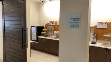 Un área de desayuno de cortesía con un cartel que indica los horarios de atención.