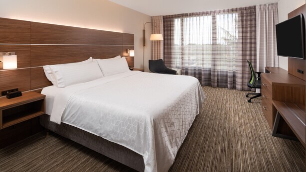 A hotel room with a large bed, a desk with a chair, a TV, and a window with curtains. - Holiday Inn Express Boca Raton-West by IHG (Boca Raton)