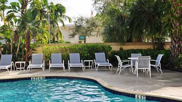 Una piscina al aire libre, sombrillas, sillones reclinables de piscina