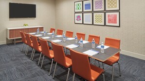 A conference room with a long table, orange chairs, water bottles, and a whiteboard.