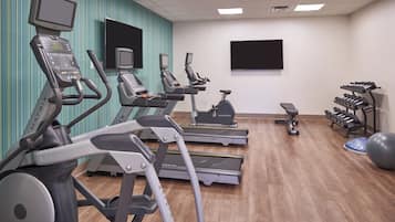 Un gimnasio con cintas de correr, elípticas y equipo de pesas.