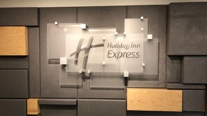 A wall with a Holiday Inn Express sign and a modern design with grey panels and wooden accents.