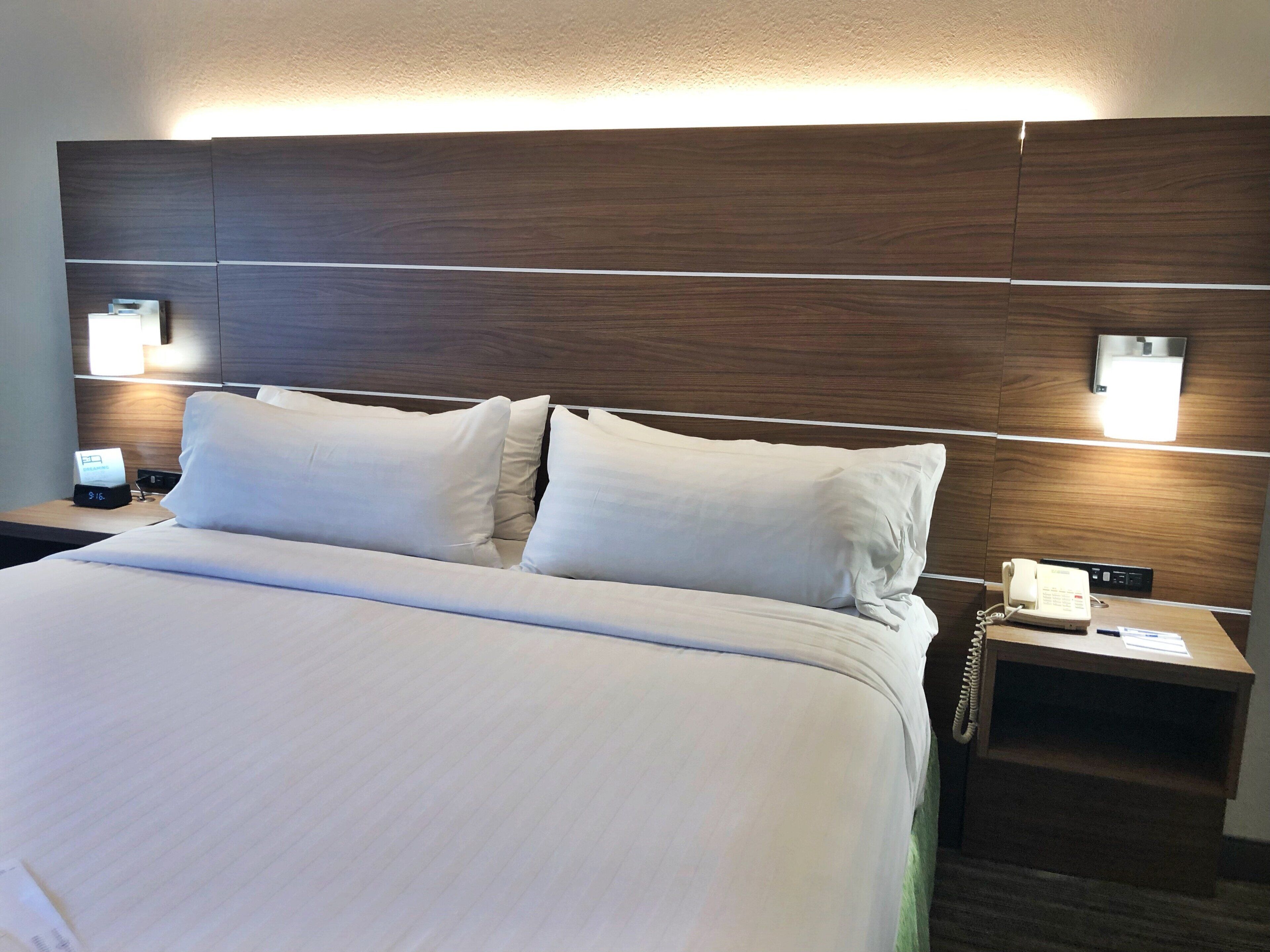 A hotel room with a large bed, two bedside tables, a nightstand, a wall-mounted TV, and a phone on the nightstand.