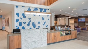 Una zona de recepción con mostrador de madera, una encimera de mármol y un muro decorado.