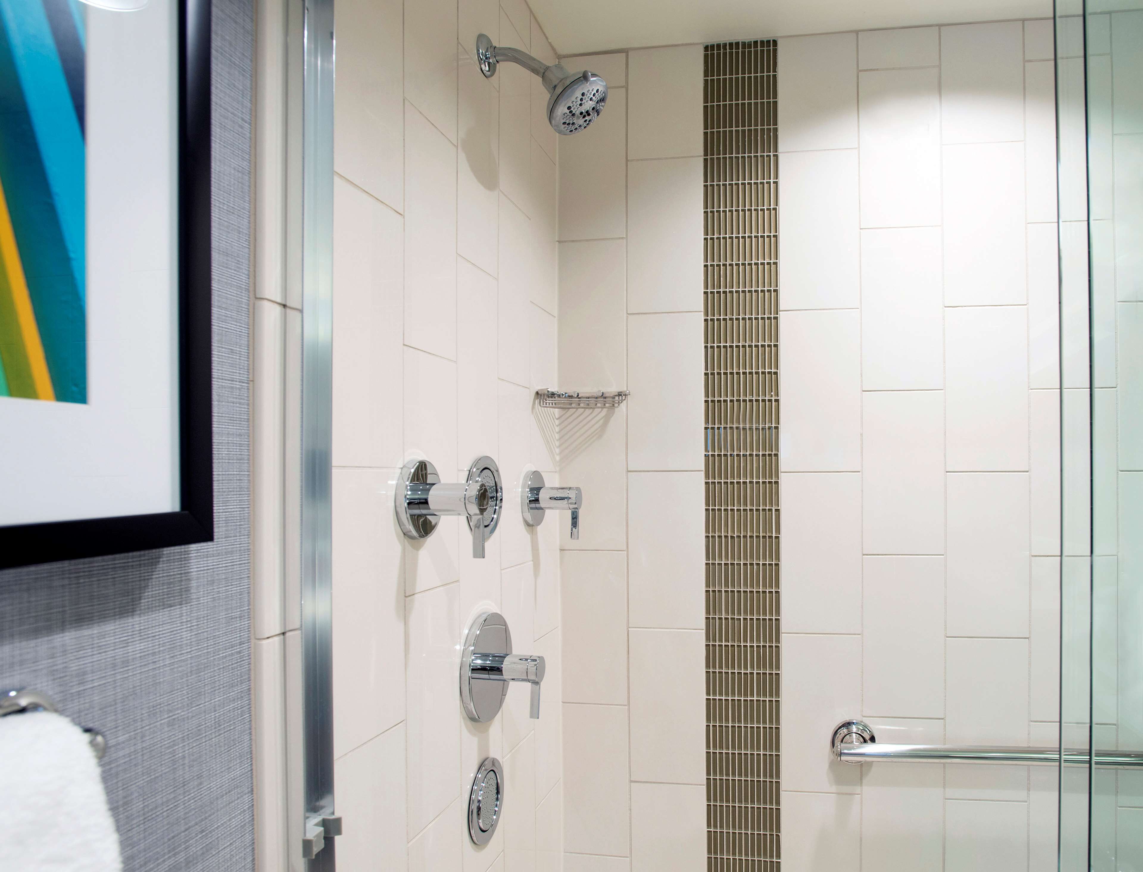 Un baño moderno con cabina de ducha de vidrio, un perchero y un inodoro.