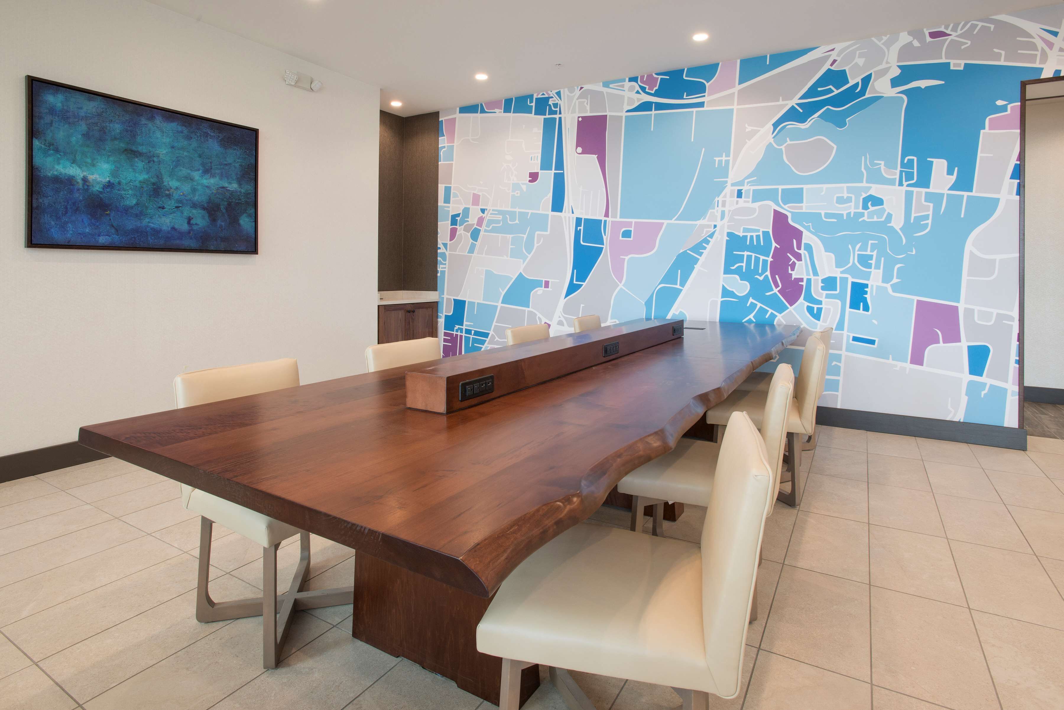 A conference room with a long wooden table, white chairs, and a map mural on the wall.