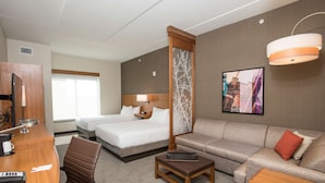 Habitación de hotel con cama, sofá, escritorio con computadora, silla y una mesita.