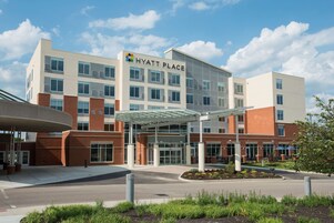 A modern hotel with a covered entrance, multiple floors, and a landscaped area in front.