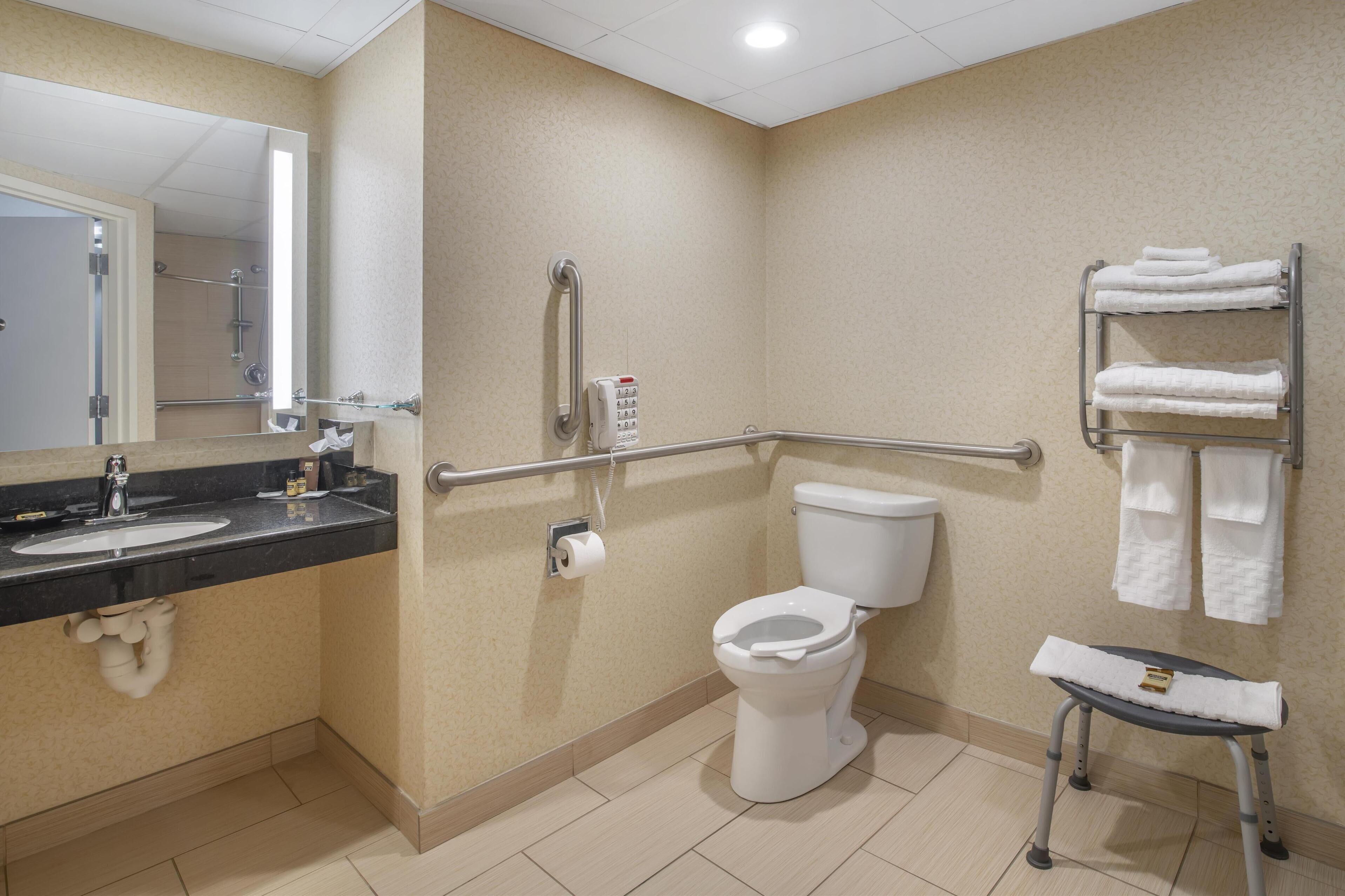 A bathroom with a sink, toilet, and handrails.