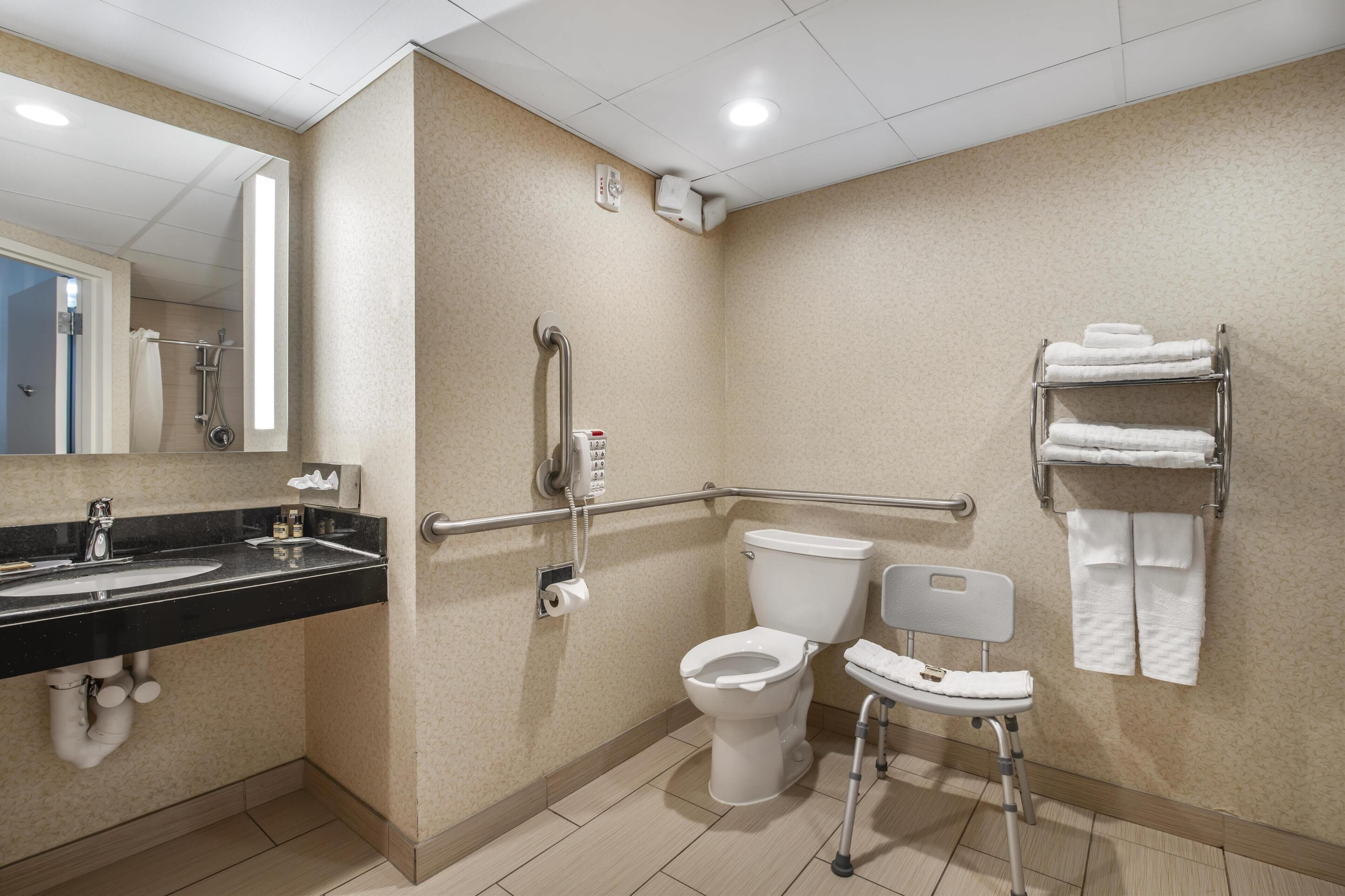 A bathroom with a sink, toilet, and handrails.