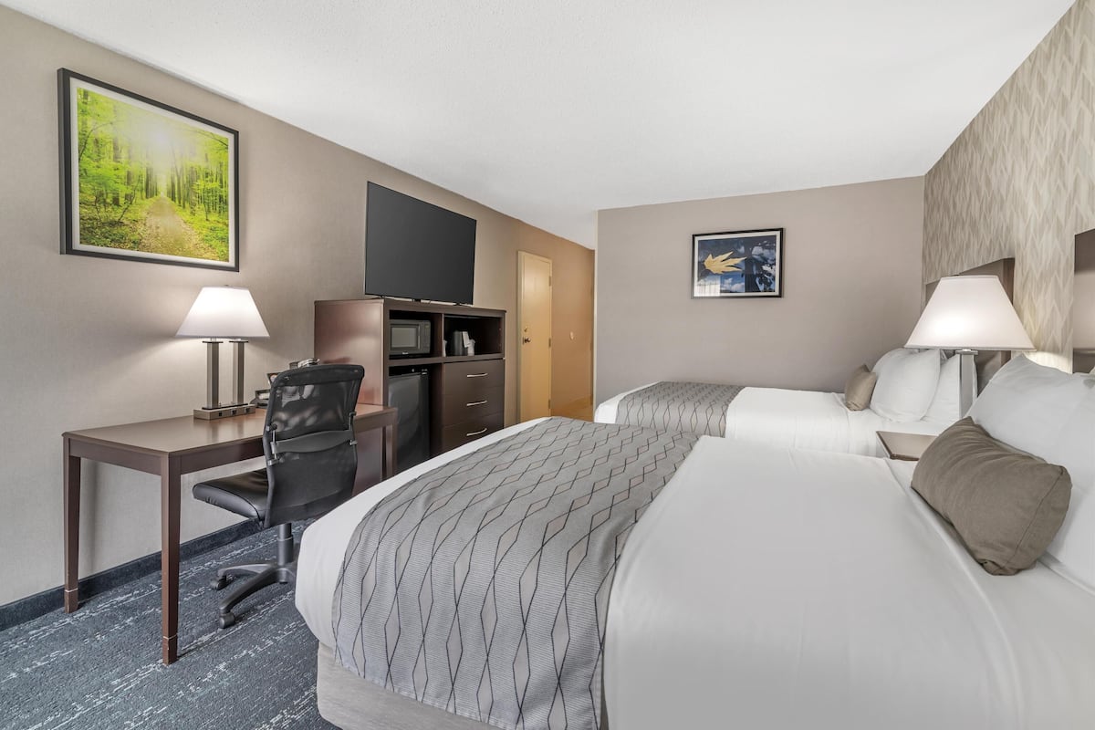 A hotel room with a bed, desk, chair, TV, and two lamps.