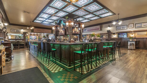 A bar area with a high ceiling and stained glass windows, bar stools, and a checkered floor. - Best Western Plus Keene Hotel (Keene)