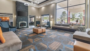 A spacious lobby with a fireplace, comfortable seating, and large windows offering a view of the outdoors. - Best Western Plus Keene Hotel (Keene)