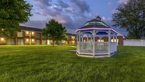 A gazebo with a white fence and a blue roof, surrounded by a well-maintained lawn, with a brick building in the background. - Best Western Plus Keene Hotel (Keene)