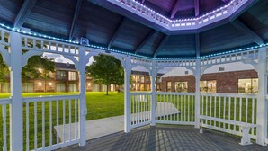 A covered outdoor area with a wooden deck, white railings, and string lights. - Best Western Plus Keene Hotel (Keene)