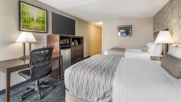 A hotel room with a bed, desk, chair, TV, and artwork on the walls.