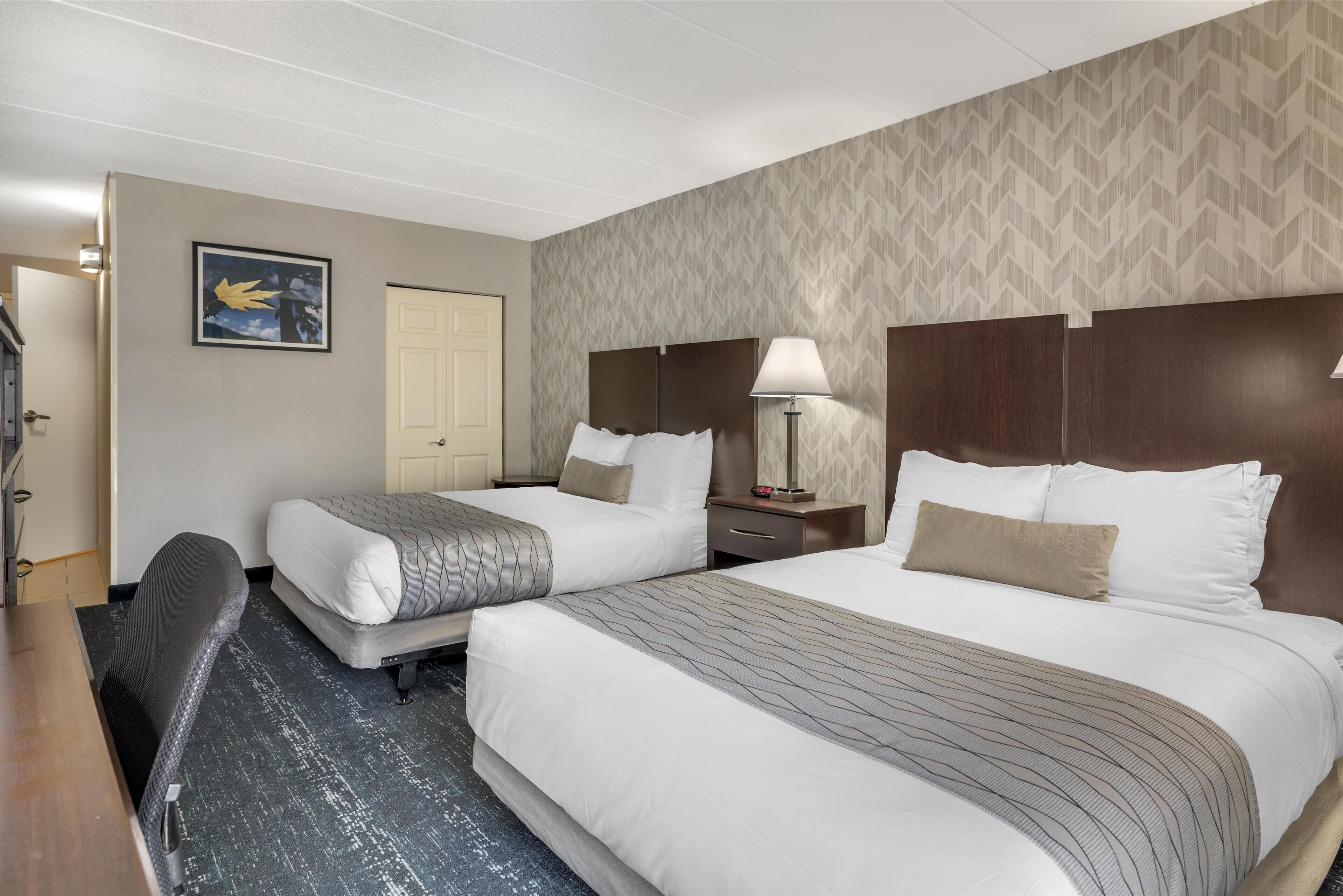 Een hotelkamer met twee bedden, een bureau, een stoel, een lamp en een deur.
