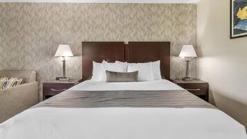 A hotel room with a large bed, two bedside tables, a nightstand, a sofa, and a patterned wallpaper.