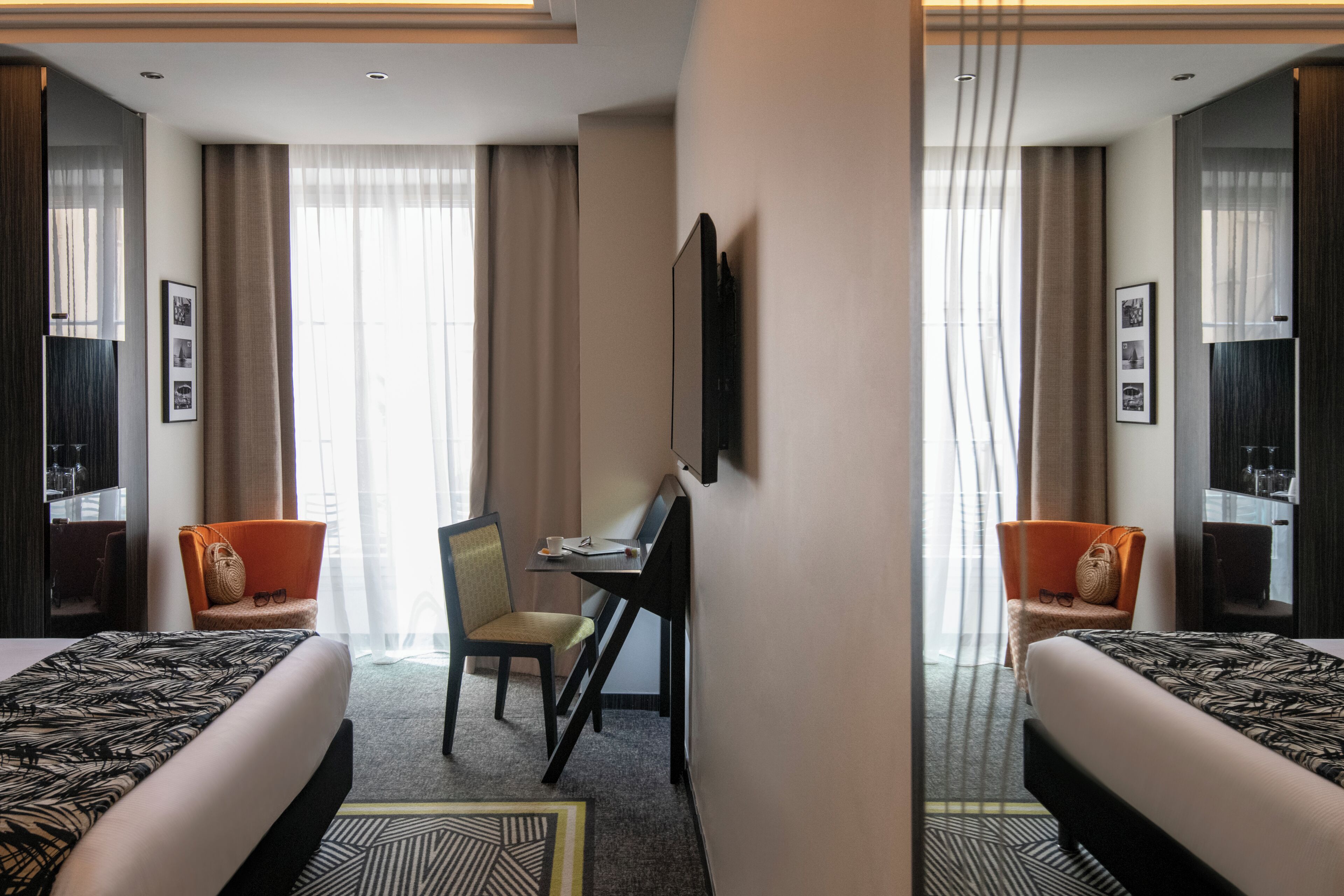 A hotel room with two beds, a desk, and a chair.