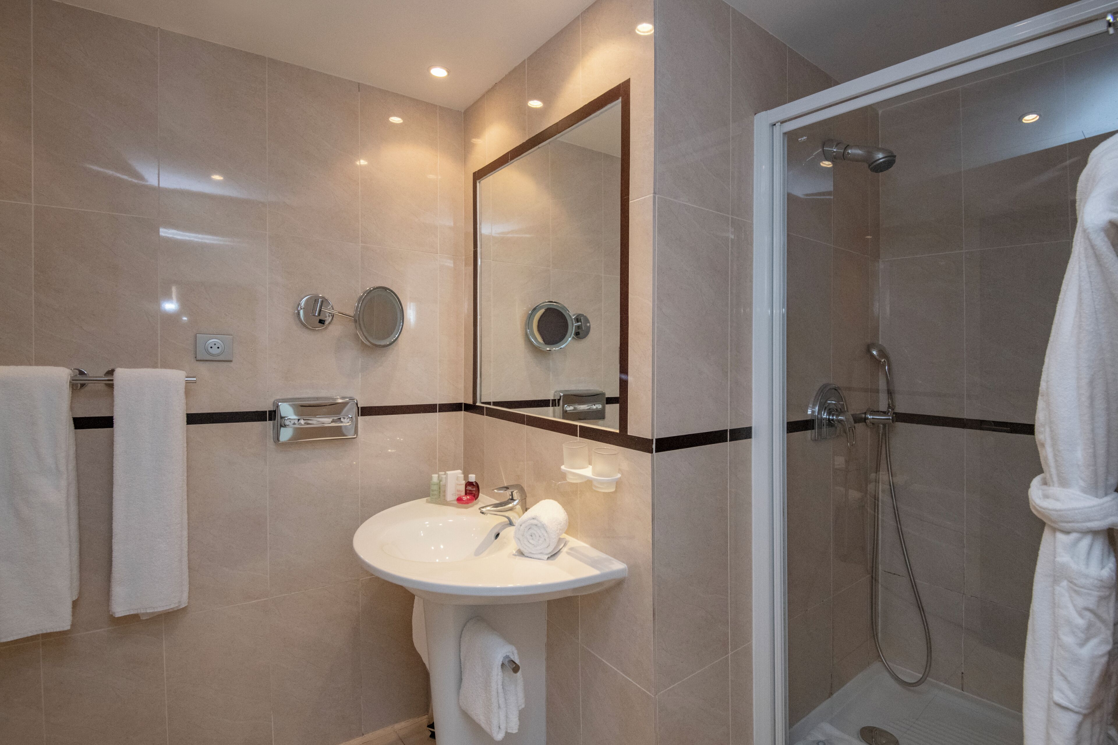 A modern bathroom with a white sink, mirror, and shower.