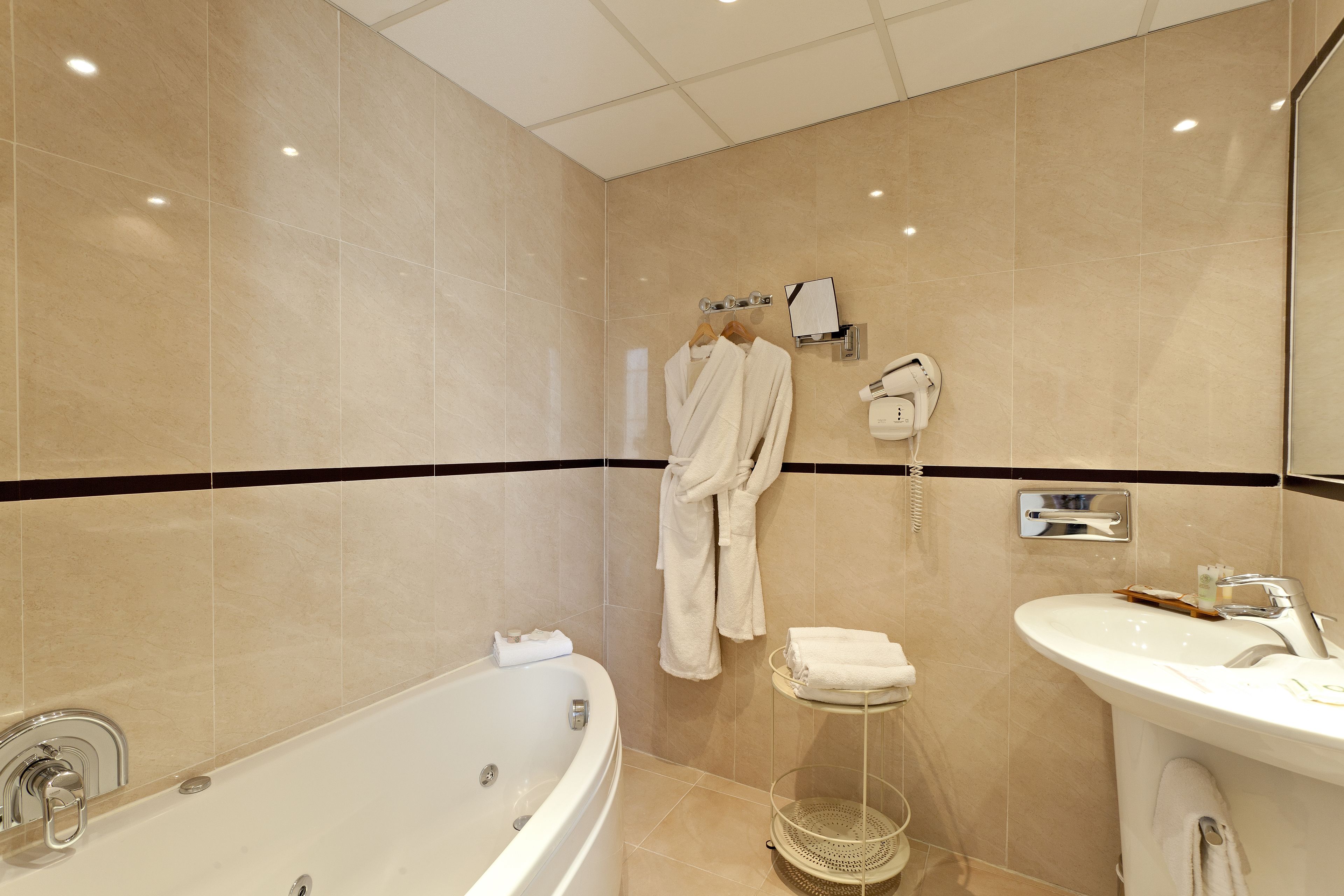 A modern bathroom with a bathtub, a sink, and a towel rack.