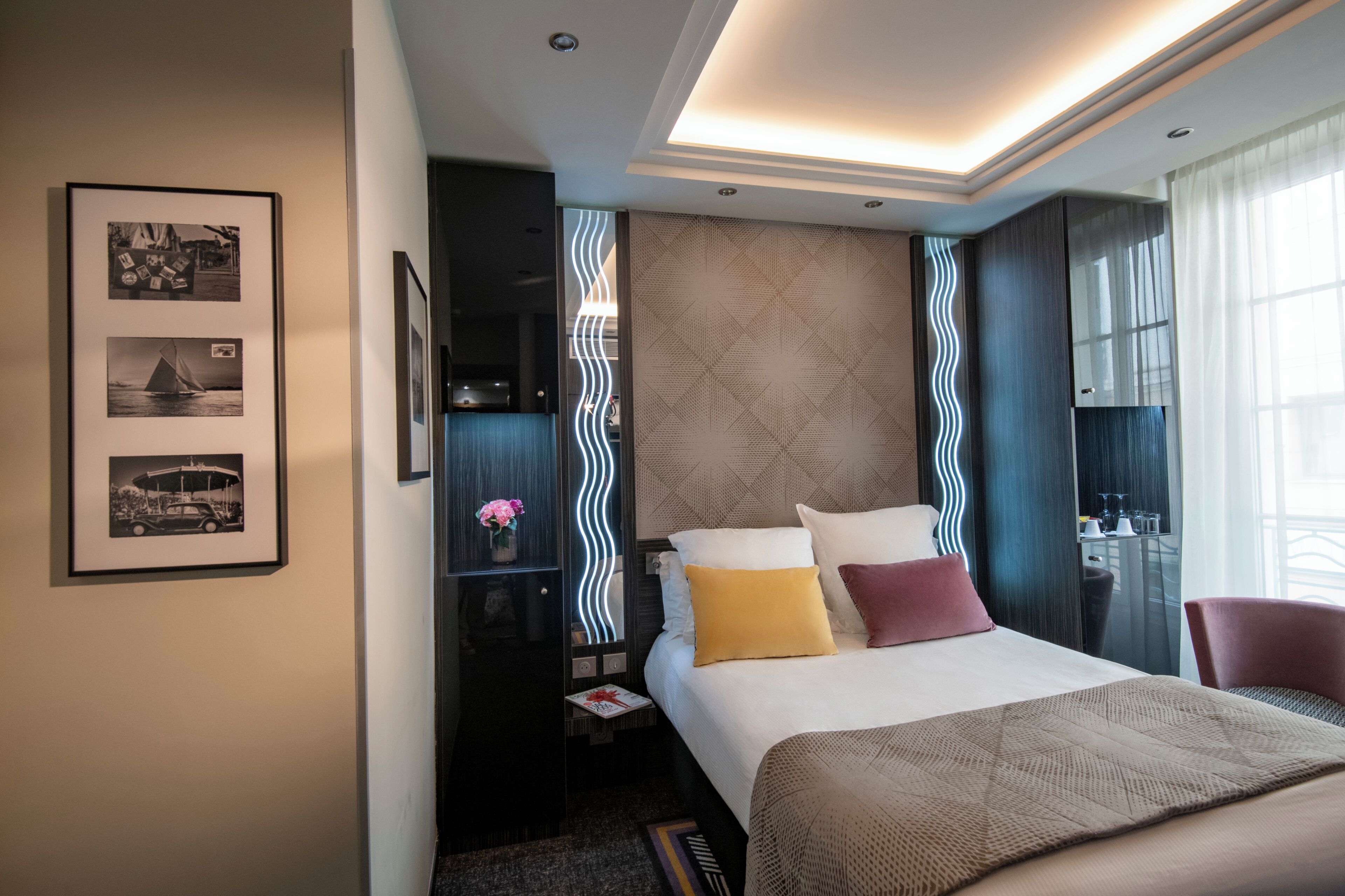 A modern hotel room with a large bed, a nightstand, a desk, and a chair.