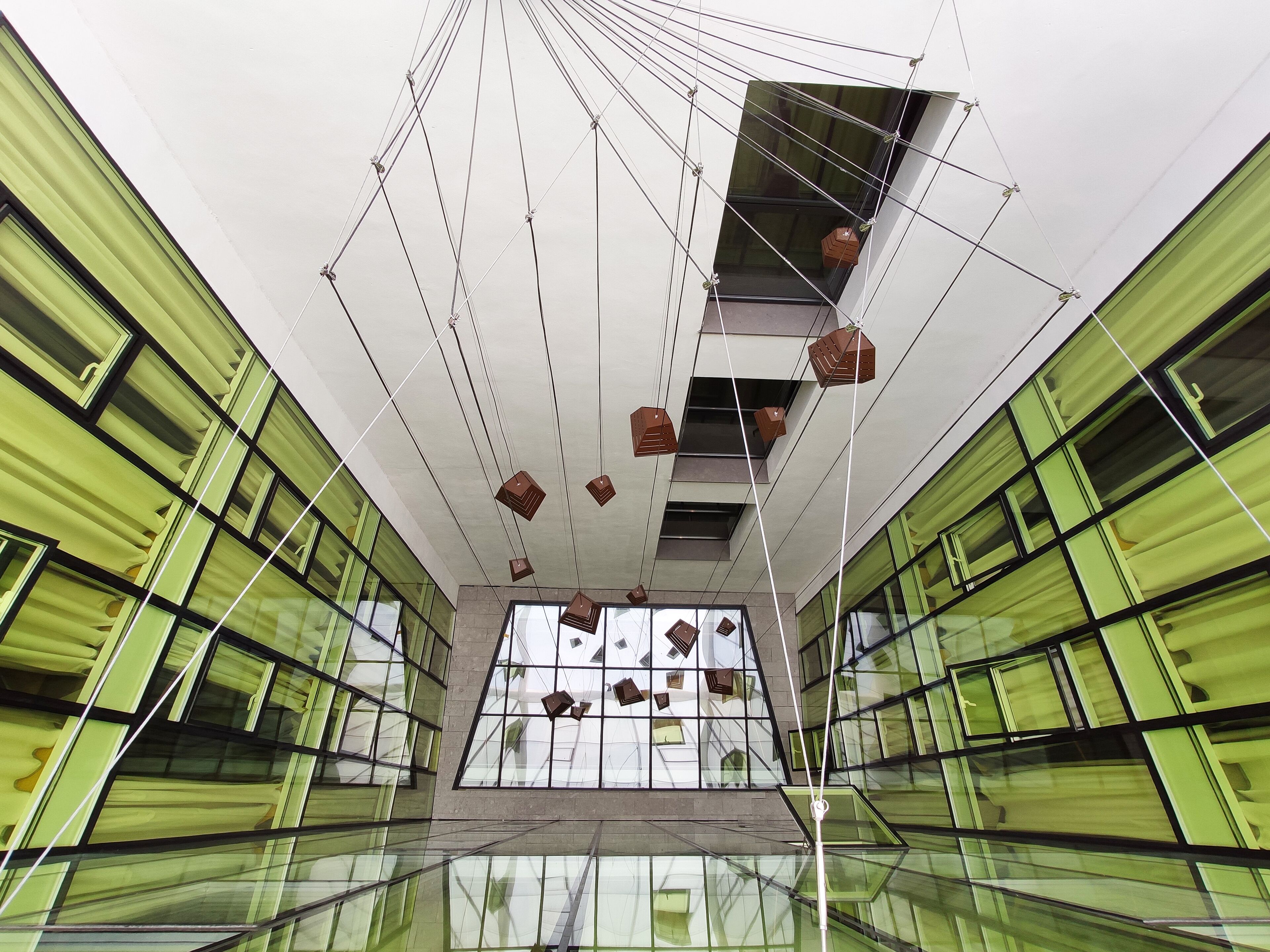 Un edificio moderno con fachada de vidrio, múltiples ventanas y lámparas colgantes.
