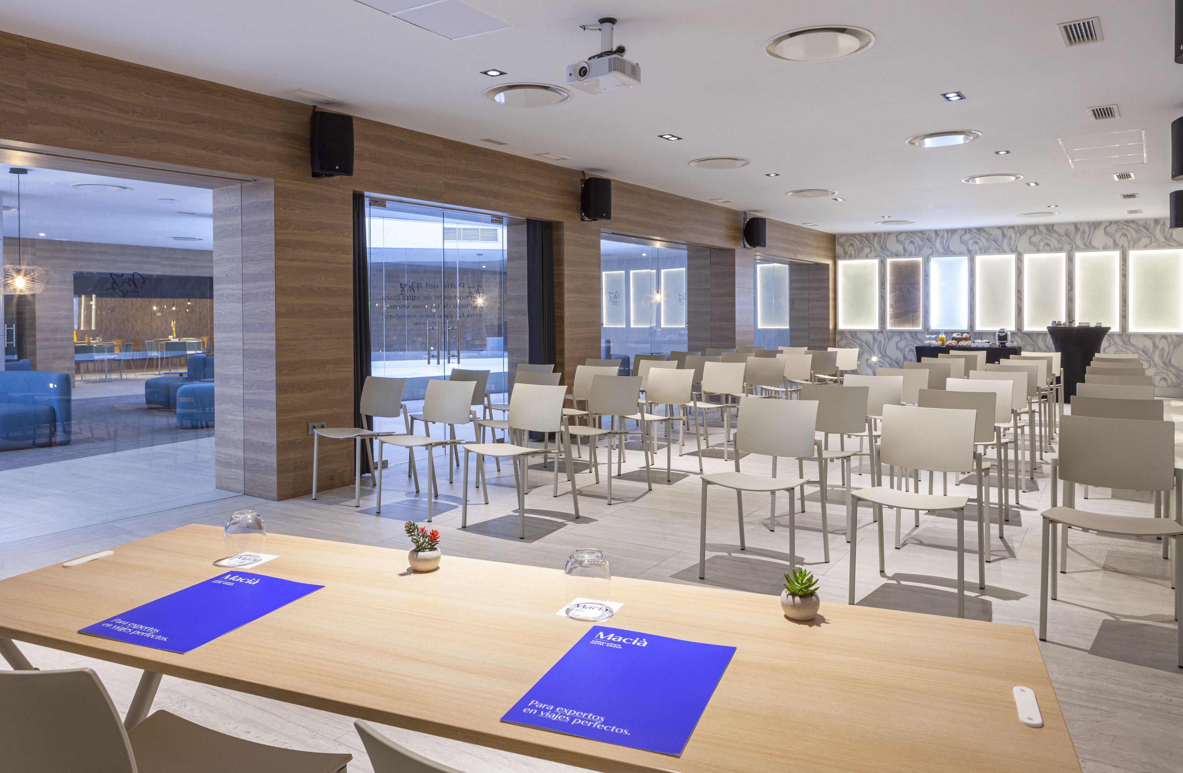 A modern conference room with a long table, multiple chairs, and a glass partition.