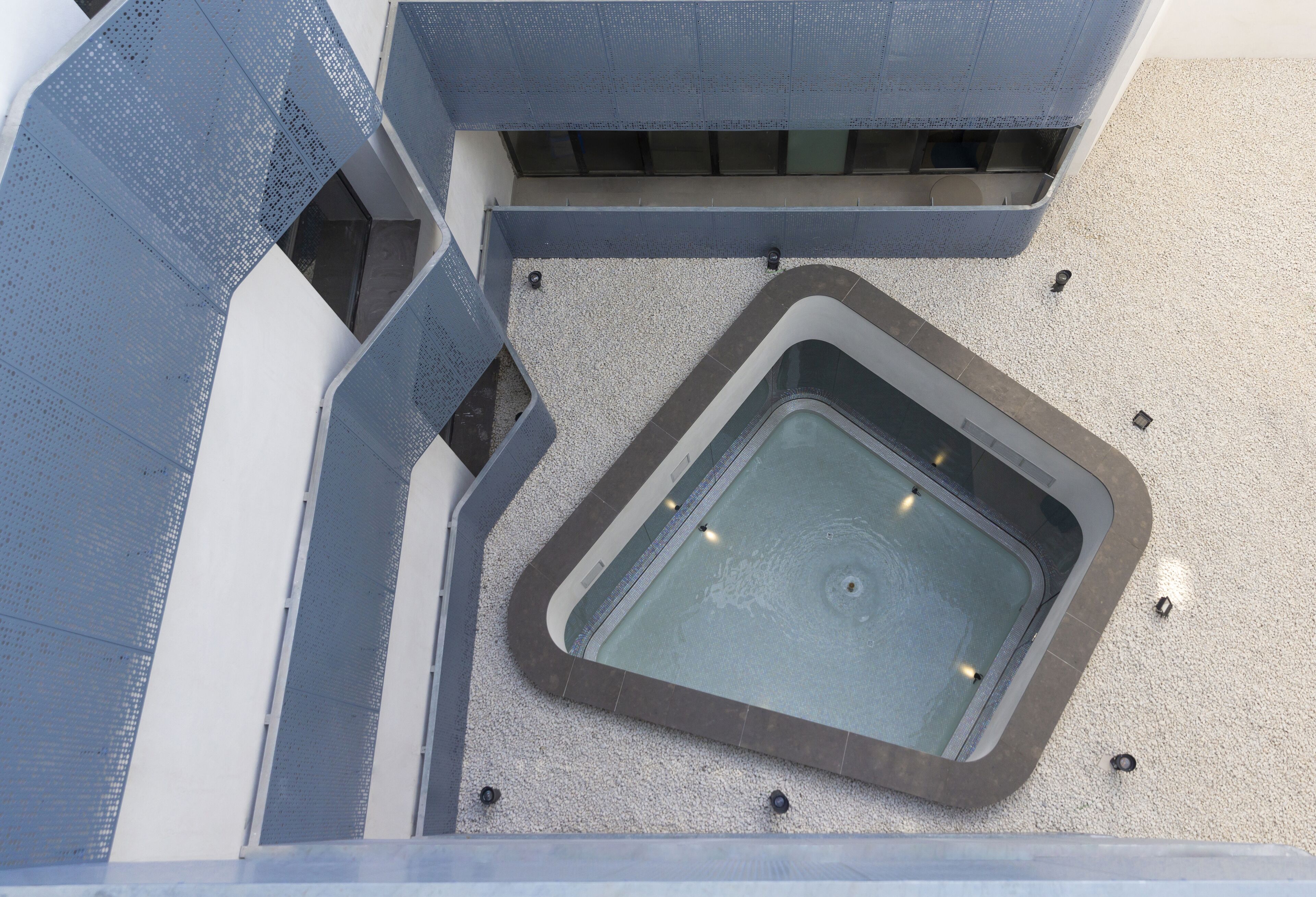 Ein Poolbereich auf dem Dach mit einem rechteckigen Pool, umgeben von einer niedrigen Mauer und einem überdachten Sitzbereich.